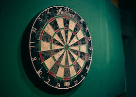 Worn dartboard on a green wall indoors, perfect for sports entertainment themes.